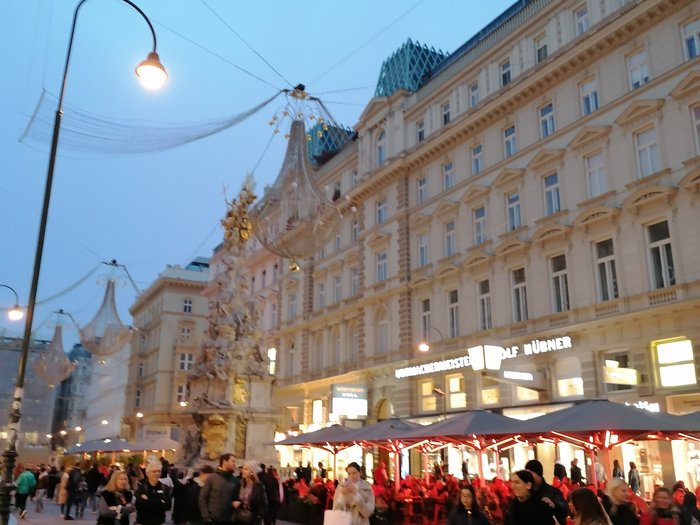 Auf Reisen: Althandwerker auf Flusskreuzfahrt Belebte Einkaufsstraße bei Abenddämmerung mit historischen Gebäuden und Menschen