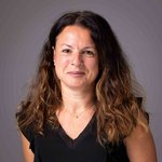 Das lvh-Team Porträt einer Frau mit braunen Haaren und schwarzem Oberteil vor grauem Hintergrund