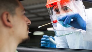 News Gesundheitspersonal führt COVID-19-Test mit Abstrich bei Person im Auto durch