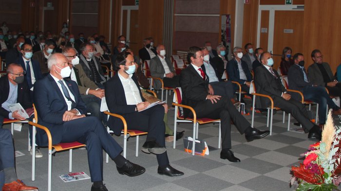 „Kinder, werdet Handwerker!“ Menschen mit Masken sitzen in einem Saal bei einer Veranstaltung