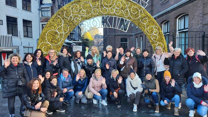 Die Frauen im Handwerk auf den Spuren van Goghs Gruppe von Menschen posiert lachend und winkend vor einem dekorativen Torbogen