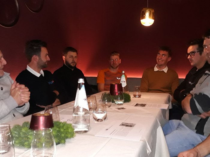 Dankesessen der Zimmerer Acht Männer sitzen an einem Tisch in einem Restaurant und unterhalten sich.