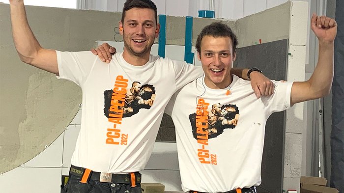 PCI-Alpencup 2022: secondo posto per i piastrellisti altoatesini! Due giovani uomini sorridono e alzano le braccia con magliette PGI-AlpenCup 2022