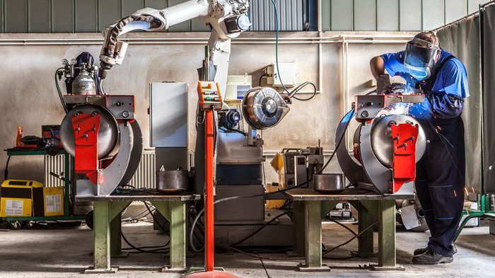 Südtiroler Exporte von Maschinen und Anlagen: sehr positive Entwicklung in den letzten 15 Jahren Schweißer arbeitet an Maschine in Industrielager mit Roboterarm