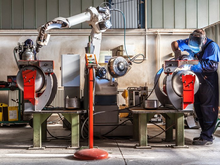 Export altoatesino di macchinari e apparecchiature: dinamica molto positiva negli ultimi 15 anni Saldatore lavora a macchina in magazzino industriale con braccio robot