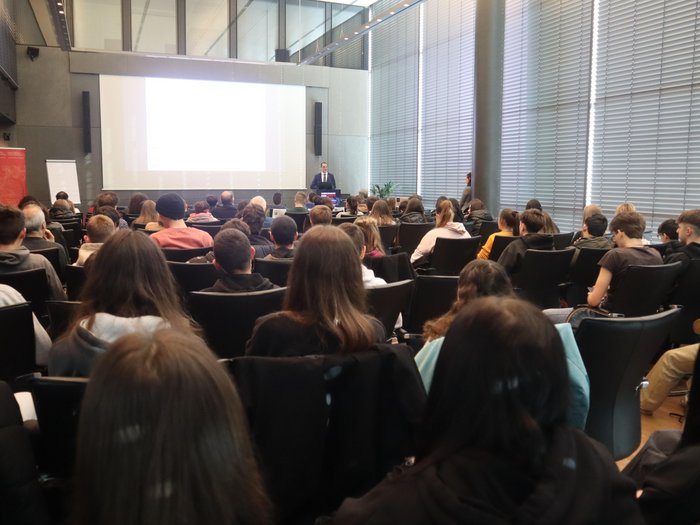 10. Wirtschaftstag für Berufsschüler/innen: eine praxisnahe Vorbereitung auf den Berufseinstieg Besucher hören einem Redner in einem modernen Konferenzraum zu