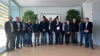 News Gruppe von 13 Männern steht in einem modernen Raum vor einem abstrakten Bild