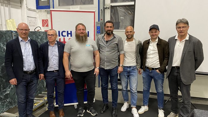 Erfolgreiche lvh-Bezirksversammlung Klausen Sieben Männer in legerer und formeller Kleidung stehen nebeneinander in einer Innenraumhalle