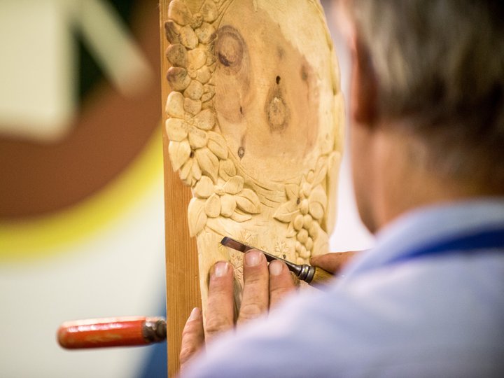 Holzschnitzer Handwerker schnitzt florale Muster in Holz mit Stechbeitel