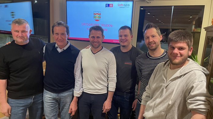 lvh Truden: Handwerk hat gewählt Sechs Männer stehen lächelnd in Innenraum vor Bildschirm mit Schrift Ortsgruppe Truden