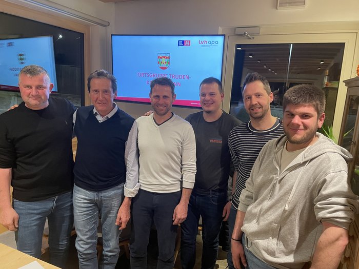 lvh Truden: Handwerk hat gewählt Sechs Männer stehen lächelnd in Innenraum vor Bildschirm mit Schrift Ortsgruppe Truden