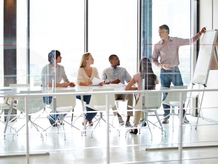 Sviluppo aziendale Team di 4 persone in riunione, una persona presenta a lavagna in ufficio
