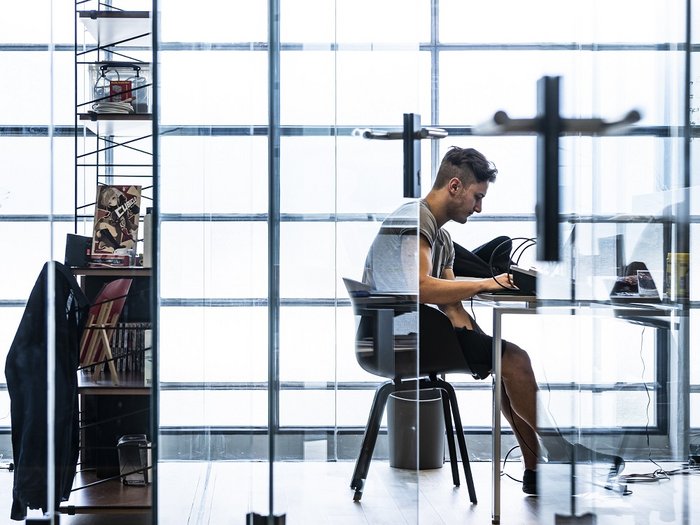 Foto: © Ivo Corrà Mann arbeitet konzentriert an einem Schreibtisch in modernem, hellem Büro