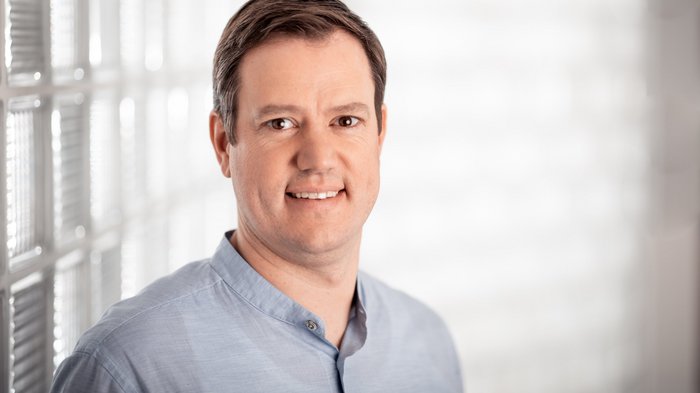 Mehr Finanzmittel für betriebliche Investitionen Porträt eines lächelnden Mannes in blauem Hemd vor hellem Hintergrund