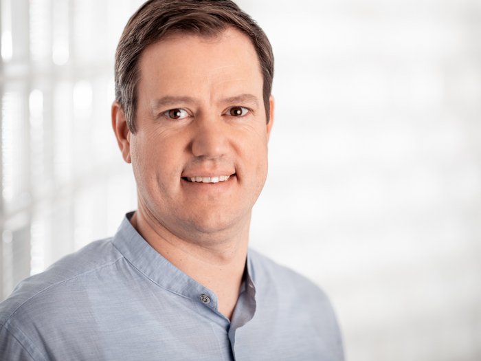 Mehr Finanzmittel für betriebliche Investitionen Porträt eines lächelnden Mannes in blauem Hemd vor hellem Hintergrund