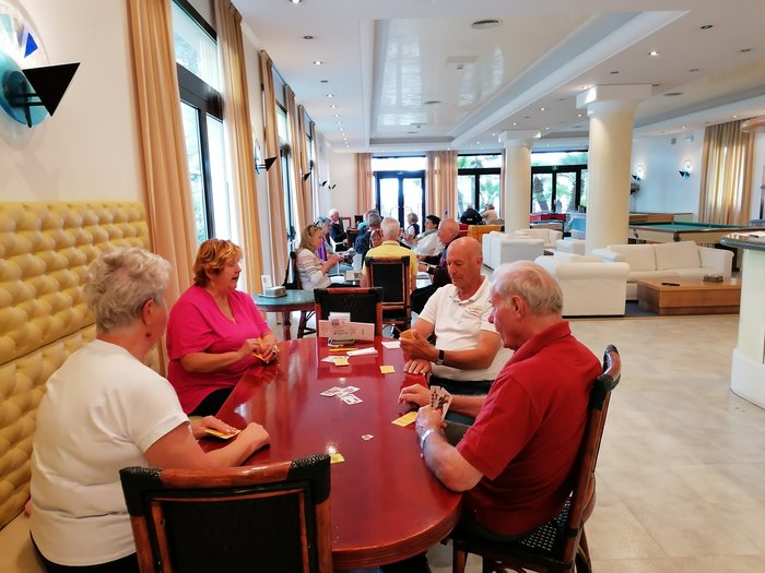 Badespaß an der Adria Senioren spielen Karten in einem hellen Gemeinschaftsraum mit Sitzbereichen und Billardtischen