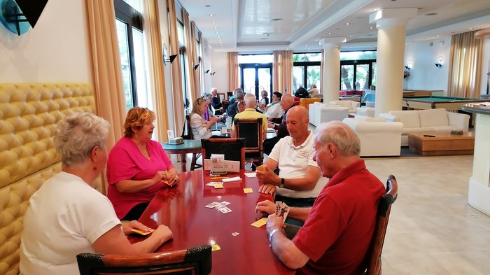 Badespaß an der Adria Senioren spielen Karten in einem hellen Gemeinschaftsraum mit Sitzbereichen und Billardtischen