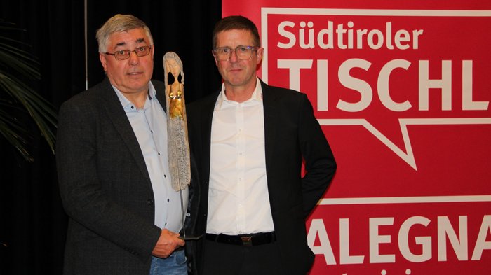 Assemblea annuale dei falegnami altoatesini: uno sguardo al futuro dell'artigianato Due uomini con trofeo davanti a sfondo rosso Südtiroler Tischler