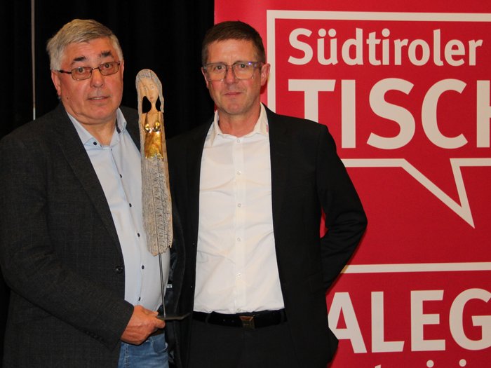 Assemblea annuale dei falegnami altoatesini: uno sguardo al futuro dell'artigianato Due uomini con trofeo davanti a sfondo rosso Südtiroler Tischler