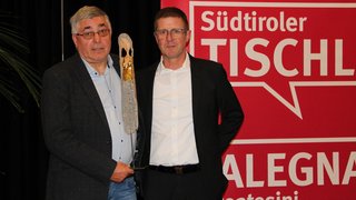 News Zwei Männer mit Trophäe vor rotem Südtiroler Tischler Hintergrund