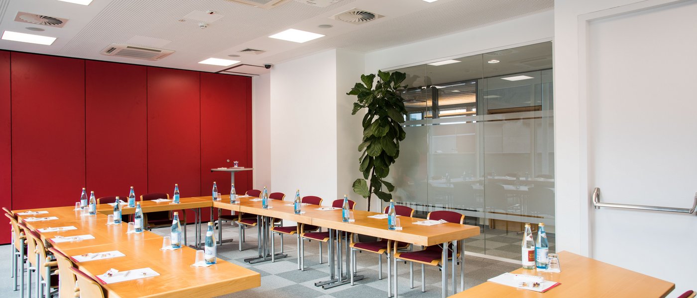 Affitto aule seminari Sala conferenze moderna con tavolo a forma di U in legno e bottiglie d'acqua