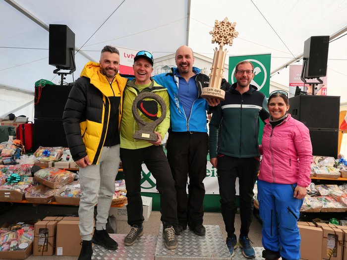 Wo Handwerk auf Pistengaudi trifft: lvh-Wintersportfest begeistert Gruppe von fünf Personen mit zwei Pokalen auf einem Podium, im Hintergrund Geschenkkörbe