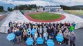 Rittner Musterschau verbindet Menschen und Ideen Große Gruppe von Menschen mit Schildern vor Sportanlage unter bewölktem Himmel