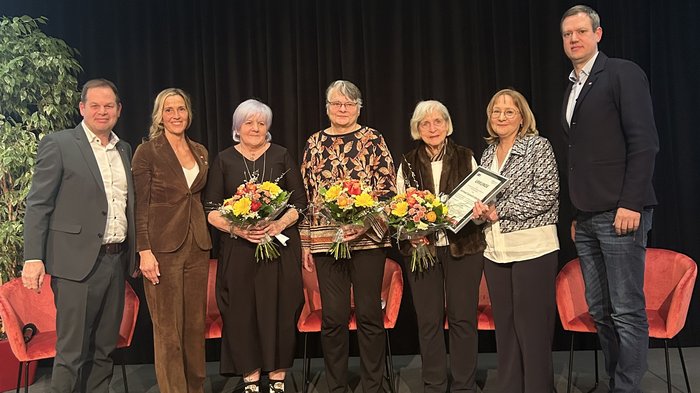 Neujahrsempfang der Frauen im Handwerk: „WIR gestalten Zukunft“ Sieben Personen stehen auf Bühne, drei Frauen halten Blumen und eine Urkunde