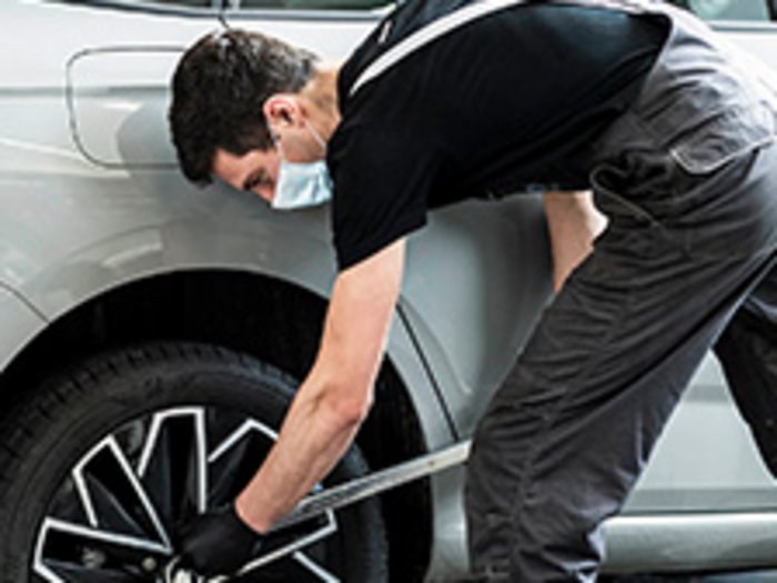 KFZ- und Karosseriewerkstätten bleiben geöffnet Mechaniker überprüft Autoreifen in moderner Werkstatt