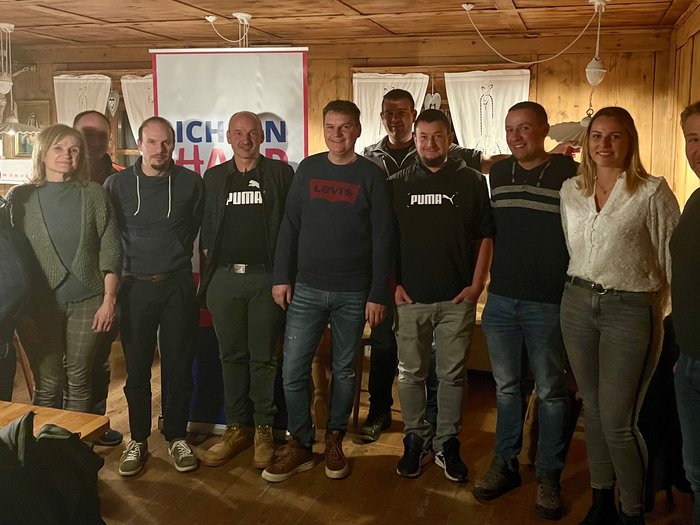 Ulrich Perkmann als Ortsobmann bestätigt Gruppe von elf Personen steht vor Banner in Holzraum