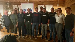 News Gruppe von elf Personen steht vor Banner in Holzraum