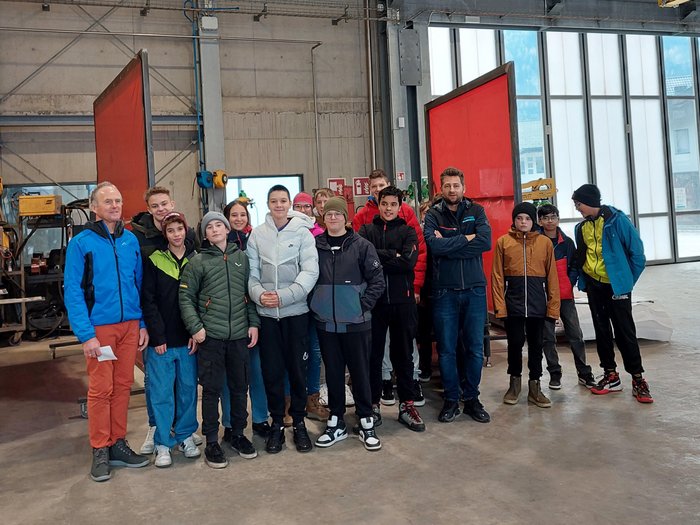 Junghandwerker/innen im lvh und Hoteliers- und Gastwirtejugend (HGJ) zu Gast in der Mittelschule Vintl Gruppe junger Menschen und zwei Erwachsene in einer Industriehalle