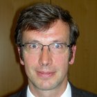 Textilreiniger Porträt eines Mannes mit Brille, Anzug und Krawatte vor braunem Hintergrund