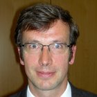 Textilreiniger Porträt eines Mannes mit Brille, Anzug und Krawatte vor braunem Hintergrund