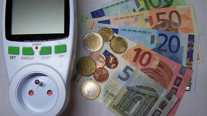 Extreme Strompreise für Unternehmen nicht nachvollziehbar Energiekostenmessgerät neben Euro-Geldscheinen und Münzen
