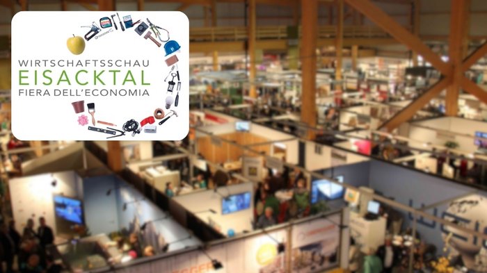 Eisacktaler Wirtschaftsschau 2024 Messestand mit Wirtschaftsschau Eisacktal Logo und Besuchern in Messehalle