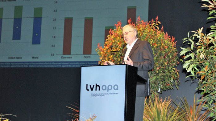 Landesversammlung des Südtiroler Handwerks Mann spricht bei lvh apa Konferenz vor Diagramm und Pflanzen