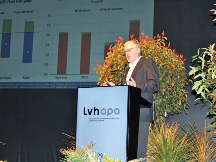 Landesversammlung des Südtiroler Handwerks Mann spricht bei lvh apa Konferenz vor Diagramm und Pflanzen