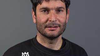 News Porträt eines Mannes mit schwarzem Pullover vor grauem Hintergrund