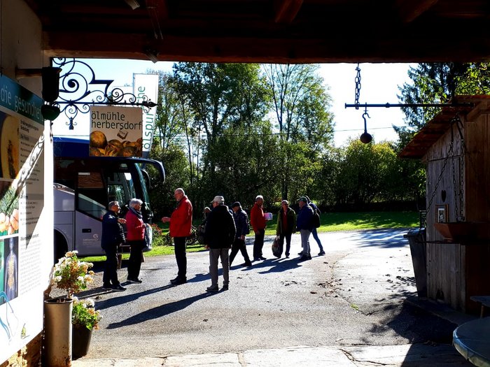 Unsere Althandwerker zu Besuch in der Stiermark Gruppe von Menschen vor dem Eingang der Ölmühle Herbersdorf an einem sonnigen Tag