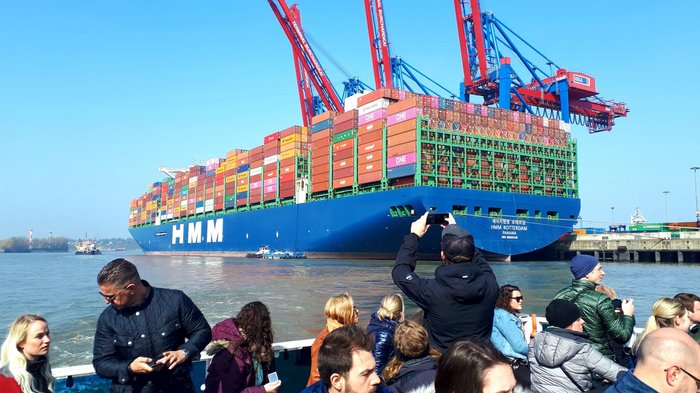 Die Althandwerker besuchen Hamburg Viele Menschen fotografieren ein großes Containerschiff mit bunten Container in einem Hafen
