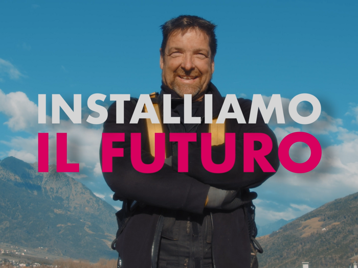 "La tutela del clima è lavoro e noi lo facciamo ogni giorno" Uomo sorridente davanti a paesaggio montano con cielo azzurro e testo Installiamo il futuro