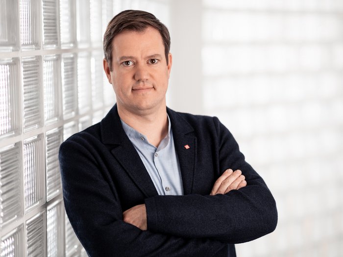 Haller: „Reine Versprechen, sonst nichts!“ Porträt eines Mannes in blauem Sakko vor Glaswand mit verschränkten Armen