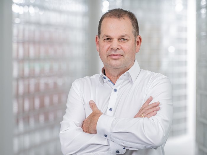 „Bozen: Fortschritte bei Mobilität, Digitalisierung und dem Dialog mit der städtischen Wirtschaft“ Porträt eines Mannes mit weißem Hemd und verschränkten Armen in hellem Raum