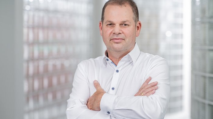 Berufsfindung leicht gemacht Porträt eines Mannes mit weißem Hemd und verschränkten Armen in hellem Raum