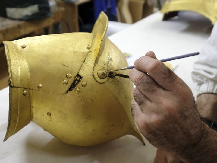 Percorso formativo Mano che restaura un elmo da cavaliere antico dorato con un pennello