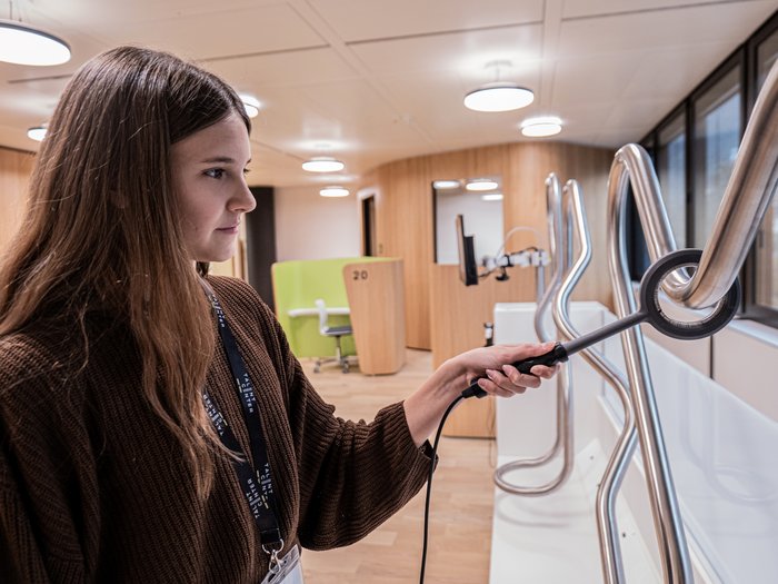 Talentcenter Bolzano: positivi i risultati dei primi sei mesi Donna esamina tubi metallici curvi con dispositivo in ufficio moderno