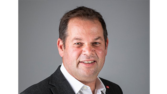 Gemeinderatswahlen 2020: Handwerker vertreten Wirtschaft und Gesellschaft Portrait eines lächelnden Mannes in weißem Hemd und dunklem Sakko vor grauem Hintergrund