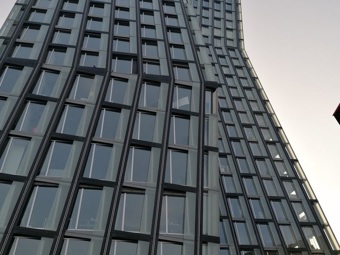 Die Althandwerker besuchen Hamburg Hohe moderne Glasfassade eines gebogenen Bürogebäudes bei klarem Himmel