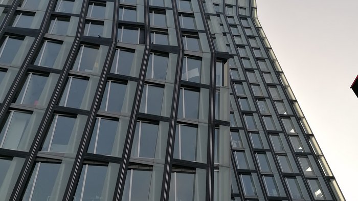 Die Althandwerker besuchen Hamburg Hohe moderne Glasfassade eines gebogenen Bürogebäudes bei klarem Himmel